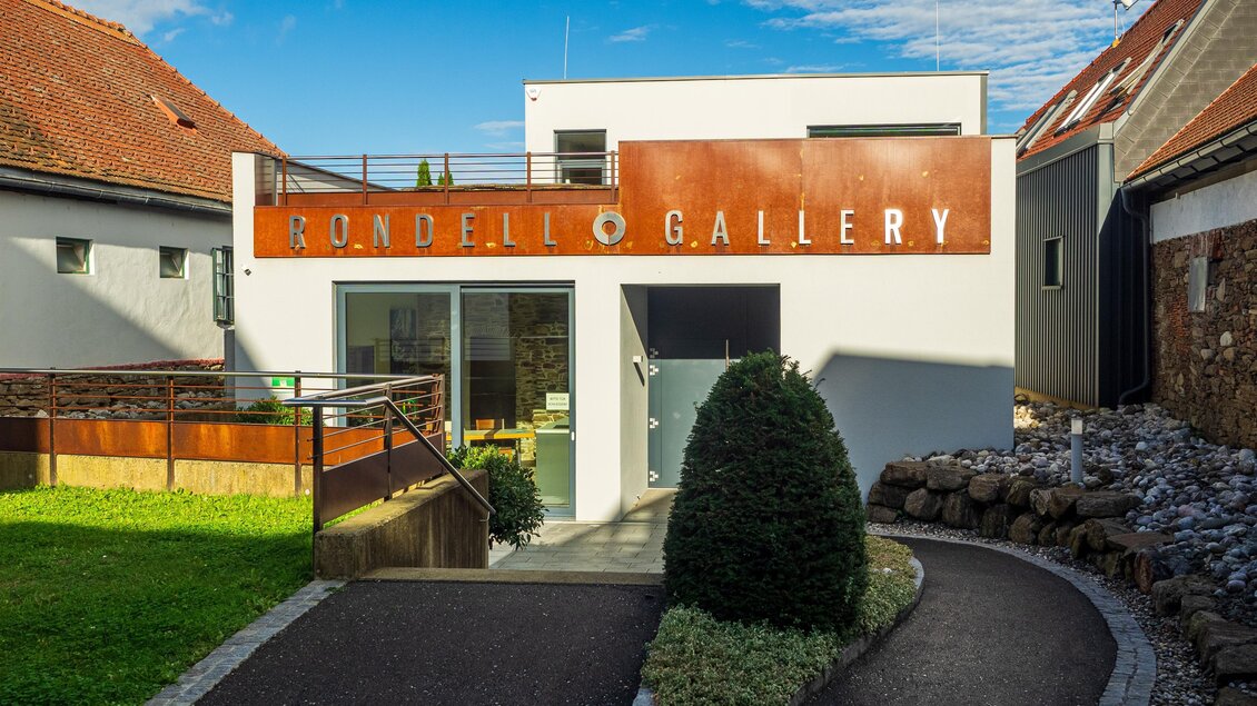 Ein modernes Galeriegebäude mit einer einladenden Eingangstür und einem gepflegten Garten. Der Himmel ist klar und die Umgebung wirkt freundlich und ruhig. | © TV Südsteiermark