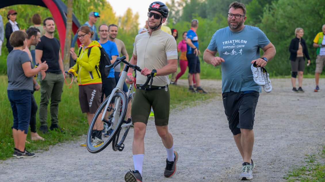 Triathlet läuft mit Rennrad zur letzten Wechselzone des eXtreme Triathlons, begleitet von Betreuern. | © Region Graz-Gerald Hirl