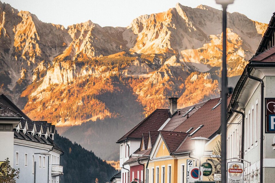 Eine ruhige Straße mit bunten Gebäuden und einem schönen Blick auf die Berge im Hintergrund. Die Szenerie strahlt eine warme Atmosphäre aus. | © Tourismusverband Gesäuse