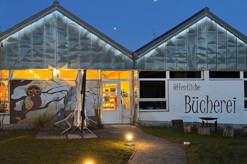 Ein modernes Gebäude mit einer großen Fensterfront, das eine öffentliche Bücherei beherbergt. Davor befindet sich ein einladender Weg mit Gartenbeleuchtung. | © Bücherei Stubenberg