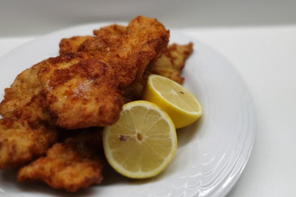 Frittierte Fischstücke auf einem weißen Teller, garniert mit frischen Zitronenscheiben. Das Gericht sieht appetitlich und knusprig aus. | © Pixabay