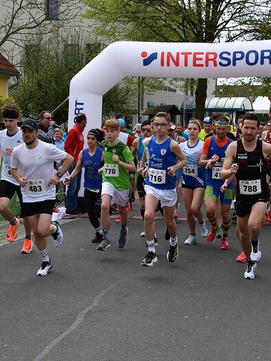 Eine Gruppe von Läufern startet einen Wettlauf unter einem großen Zelt mit dem Logo von Intersport. Im Hintergrund stehen Zuschauer und feiern die Teilnehmer. | © MSC Bad Blumau Lauffestival