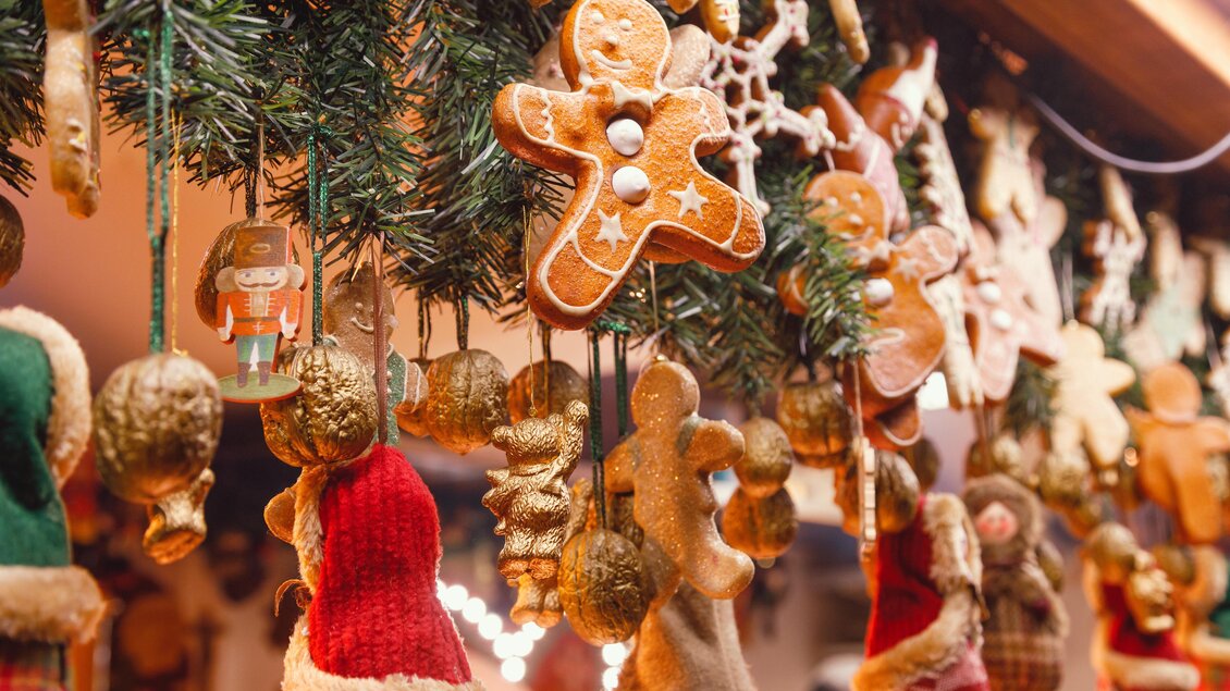 Bunte Weihnachtsdekoration mit Lebkuchenmännern und kleinen Socken. Die festliche Atmosphäre wird durch Tannenzweige ergänzt. | © AdobeStock