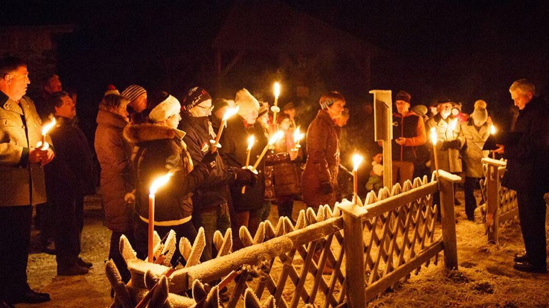 Eine Gruppe von Menschen versammelt sich nachts in einem frostigen Außenbereich. Sie halten Fackeln und stehen vor einem Holzzaun. | © Bergbauverein Öblarn