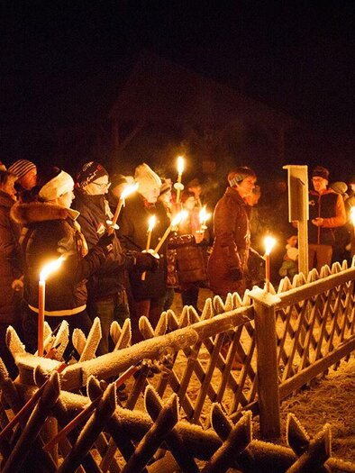 Eine Gruppe von Menschen versammelt sich nachts in einem frostigen Außenbereich. Sie halten Fackeln und stehen vor einem Holzzaun. | © Bergbauverein Öblarn