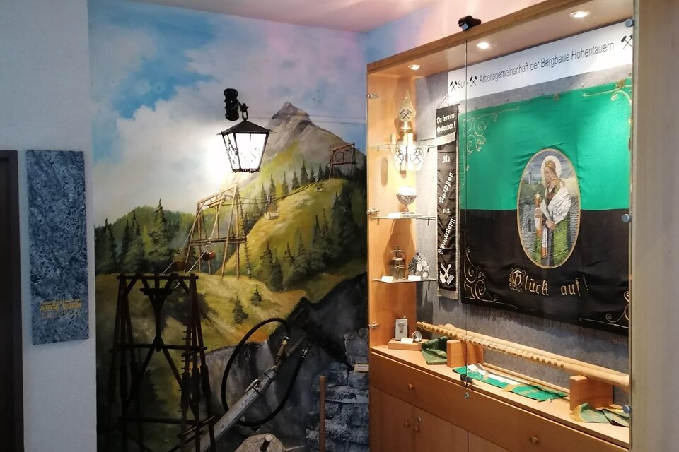 Ein Raum mit einer Wandmalerei von einer Landschaft und einer Vitrine mit historischen Objekten. Die Atmosphäre ist ruhig und einladend. | © Marlene Zandl