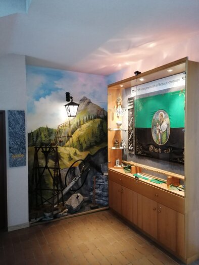 A room with a mural of a landscape and a display case with historical objects. The atmosphere is calm and inviting. | © Marlene Zandl