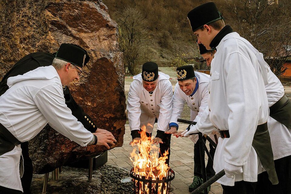Sechs Personen in weißen Anzügen stehen um ein Feuer. Sie scheinen an einer Feier oder Tradition teilzunehmen. | © Norbert Schmidt