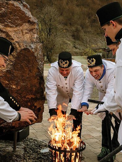 Sechs Personen in weißen Anzügen stehen um ein Feuer. Sie scheinen an einer Feier oder Tradition teilzunehmen. | © Norbert Schmidt