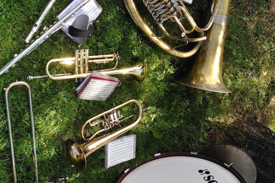 Eine Ansammlung von Musikinstrumenten liegt auf grünem Gras. Zu sehen sind eine Tuba, Trompeten, eine Posaune, eine Flöte und eine Trommel. | © Marlene Zandl