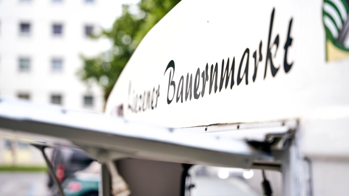 Ein Marktstand mit der Aufschrift "Kleiner Bauernmarkt". Der Stand steht in einem urbanen Umfeld. | © TV Liezen
