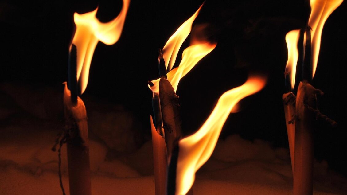 Flammen lodern von mehreren Kerzenstümpfen in der Dunkelheit. Die glühenden Flammen erzeugen eine warme, stimmungsvolle Atmosphäre. | © Pixabay