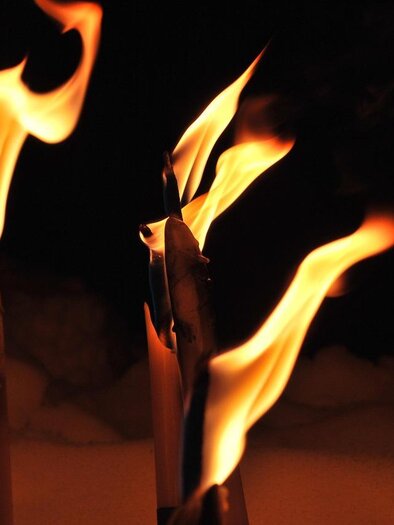 Flammen lodern von mehreren Kerzenstümpfen in der Dunkelheit. Die glühenden Flammen erzeugen eine warme, stimmungsvolle Atmosphäre. | © Pixabay