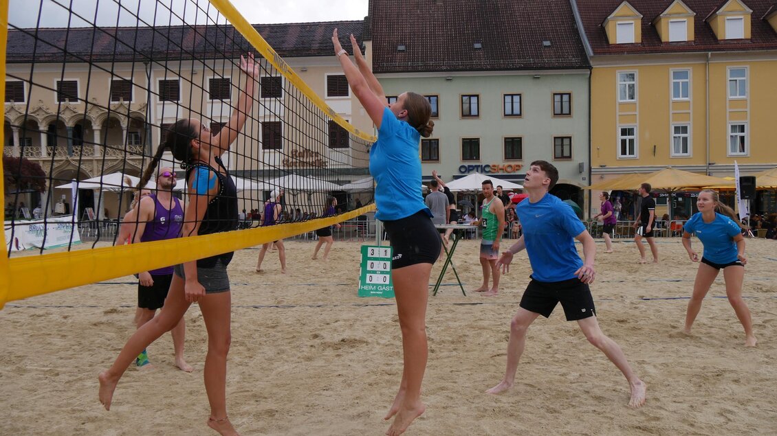 Eine Gruppe von Beachvolleyballspielern spielt am Strand. Im Hintergrund sind historische Gebäude und entspannte Atmosphäre zu sehen. | © Laura Schneller