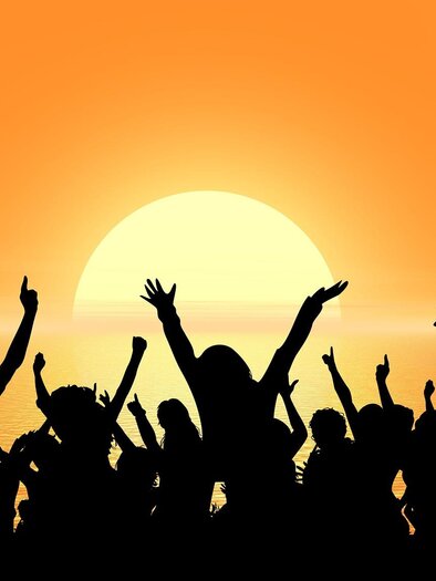 A group of people in silhouette raises their arms and celebrates in front of a colorful, glowing background. The atmosphere is cheerful and energetic. | © Pixabay