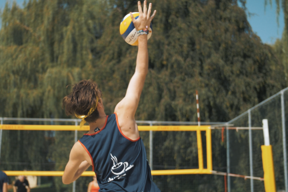 Ein männlicher Spieler bereitet sich auf einen Sprungaufschlag im Volleyballspiel vor. Im Hintergrund sind ein Volleyballfeld und große Bäume zu sehen. | © TV Region Graz-M.Dörflinger