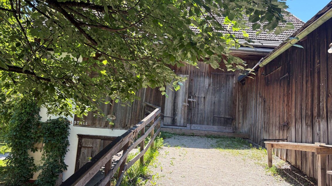 <p>Die Auffahrt zum Scheuenentor des Woferlstalls in Bad Mitterndorf. Die Scheune ist ein uriges, altes Gebäude. Der untere Teil ist weiß gemauert und der obere Teil besteht aus alten Holzbrettern. Der Himmel strahlt blau und ein paar grüne Äste eines Baumes ragen ins Bild.  </p> | © Sabine Carstensen