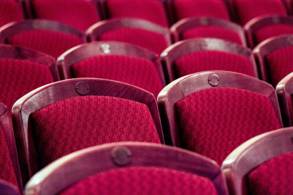 Rote Theaterstühle in Reihen angeordnet. Die Stühle haben eine weiche Polsterung und eine elegante Holzverkleidung. | © Pixabay