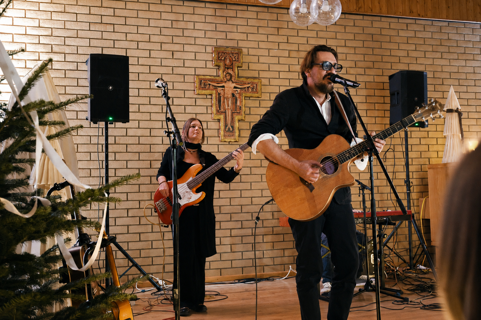Ein Sänger spielt akustische Gitarre auf einer Bühne, während eine Bassistin ihn begleitet. Im Hintergrund sind dekorative Lichter und eine Tanne zu sehen. | © LTR Thermenresort Loipersdorf GmbH