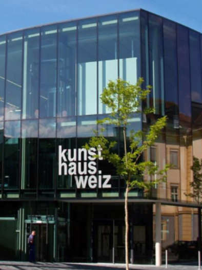 Ein modernes Gebäude mit Glasfassade, das Kunsthaus Weiz genannt wird. Es spiegelt die umliegende Architektur und Natur wider. | © Oststeiermark Tourismus