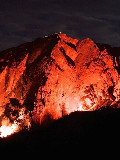 An impressive mountain landscape at night, illuminated by orange light. The rocks appear strong and dramatic in the darkness. | © Fremdenverkehrsverein Altaussee