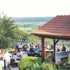 <p>Wenn sich der Blick über die sanften Hügel des Thermen- & Vulkanlandes öffnet und die Abendsonne die Landschaft in warmes Licht taucht, beginnt ein Fest, das alle Sinne berührt – das Bergfest beim Weingut Kapper in Fehring.<br/><br/>Zwischen Reben, guter Gesellschaft und einem Glas Wein in der Hand entsteht diese besondere Leichtigkeit. Gespräche fließen, Lachen klingt über die Terrasse, und die Seele darf einfach ankommen. Ein Ort, an dem Genuss und Lebensfreude ganz selbstverständlich zusammenfinden.<br/><br/>Ein Moment hoch über dem Alltag – stimmungsvoll, genussvoll und einfach zu schön, um nicht da zu sein.</p> | © Weingut Kapper