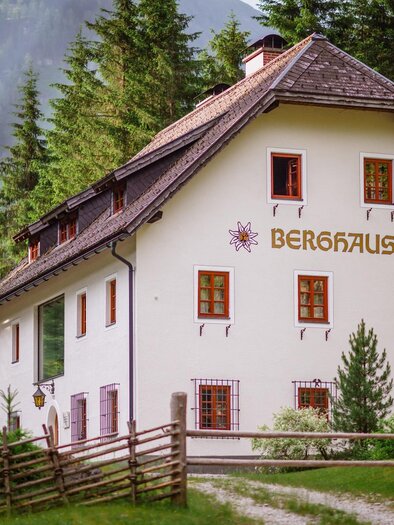 Ein hübsches Berghaus umgeben von dichten Bäumen. Das Gebäude hat große Fenster und eine traditionelle alpine Architektur. | © Christoph Huber