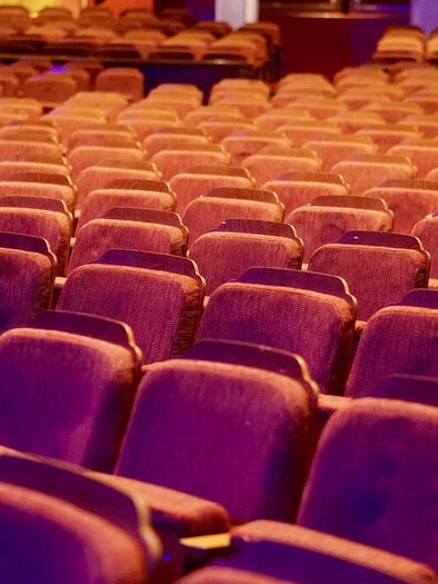 A tastefully designed theater hall with many red seats. The rows are neatly arranged and radiate an inviting atmosphere. | © Pixabay