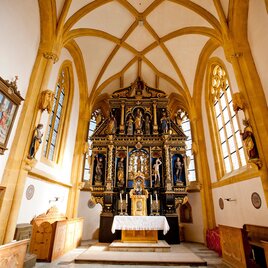 Eine schmuckvolle Kirche mit einem kunstvollen Altar im gesperrten Design. Helle Fenster und Holzdecken verleihen dem Raum eine warme Atmosphäre.
