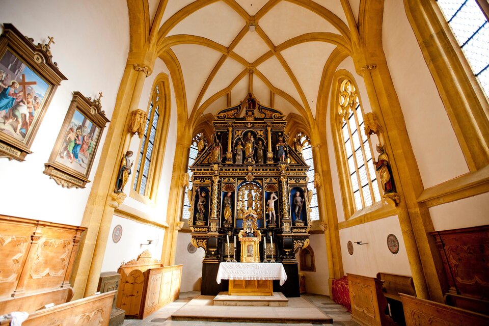 Eine schmuckvolle Kirche mit einem kunstvollen Altar im gesperrten Design. Helle Fenster und Holzdecken verleihen dem Raum eine warme Atmosphäre.