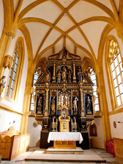 Eine schmuckvolle Kirche mit einem kunstvollen Altar im gesperrten Design. Helle Fenster und Holzdecken verleihen dem Raum eine warme Atmosphäre.