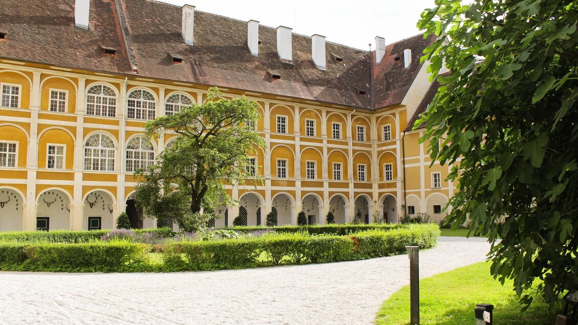 Ein historisches Gebäude mit gelber Fassade und großen Fenstern. Umgeben von gepflegten Grünflächen und Bäumen. | © TV Südsteiermark - Irene Löschnig