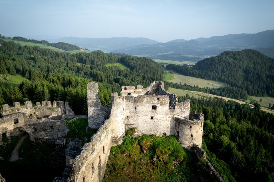Eine alte Burg auf einem Hügel mit grünen Wäldern und sanften Hügeln im Hintergrund. Die Aussicht ist weit und beeindruckend. | © TV Murau
