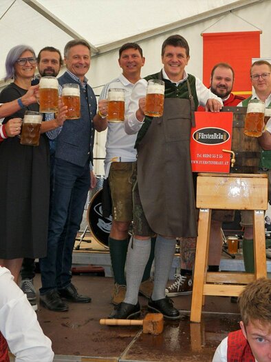 Eine Gruppe von Männern und Frauen in traditioneller Tracht hält große Bierkrüge. Sie feiern fröhlich in einem festlichen Zelt. | © © Stadtmarketing Fürstenfeld
