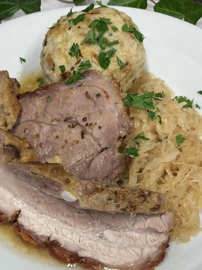 A plate with juicy roast pork, served with sauerkraut and a dumpling. The dish is garnished with fresh parsley. | © Popp'n Angerl, Familie Heiß