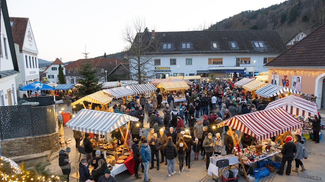 Ein lebhafter Weihnachtsmarkt mit vielen Menschen und bunten Ständen. Lichter und festliche Dekorationen schaffen eine gemütliche Atmosphäre. | © Verein Wirtschaftsregion Anger