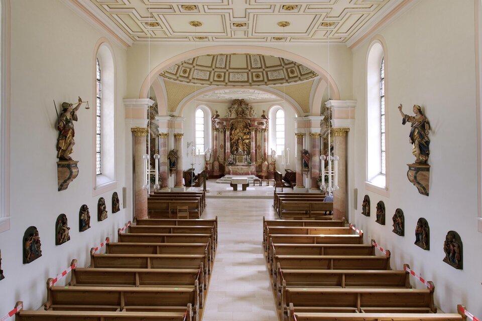 Eine ruhige Kirche mit Holzbänken und buntem Altar. Der Raum ist hell erleuchtet und zeigt kunstvolle Details an Wänden und Decke. | © Pixabay