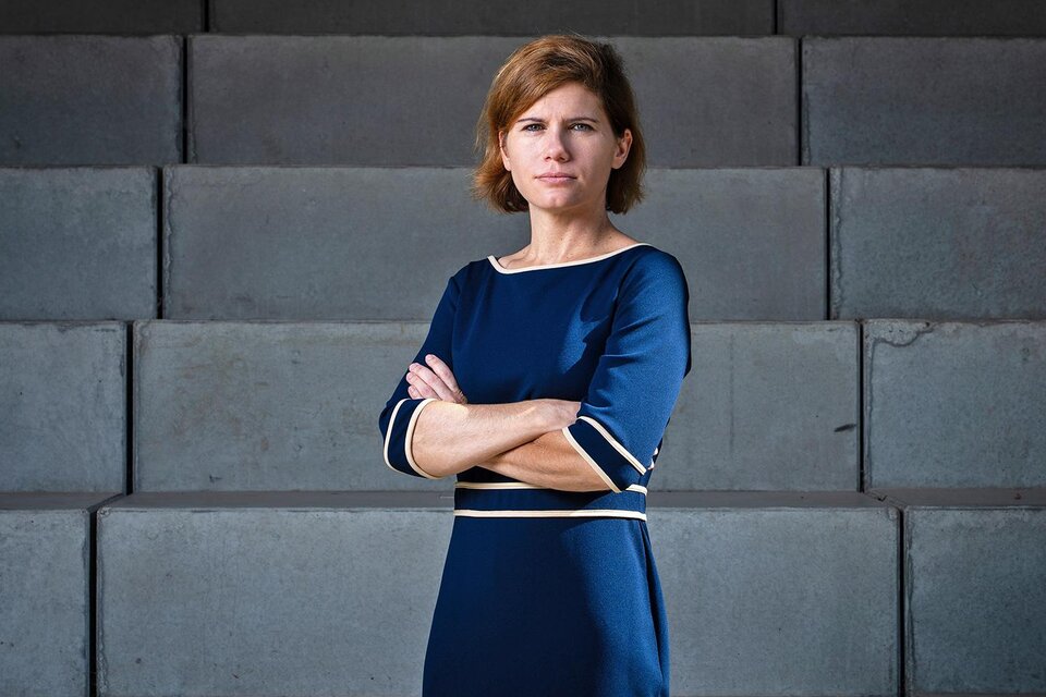 Eine Frau in einem blauen Kleid steht mit verschränkten Armen vor einer grauen Wand. Ihr Blick ist ernst und sie strahlt Selbstbewusstsein aus. | © Gianmaria Gava