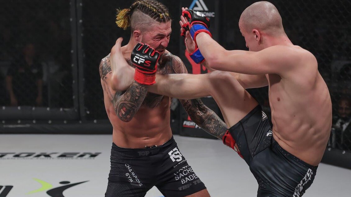 Zwei Kämpfer im Oktagon während eines MMA-Matches. Der Kämpfer mit geflochtenem Haar trifft seinen Gegner mit einem hohen Kick. | © Bobipix