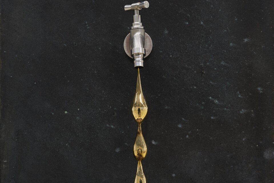 Ein Wasserhahn an einer dunklen Wand. Goldene Tropfen hängen von der Auslassöffnung. | © (c)Jean-Christophe Lett