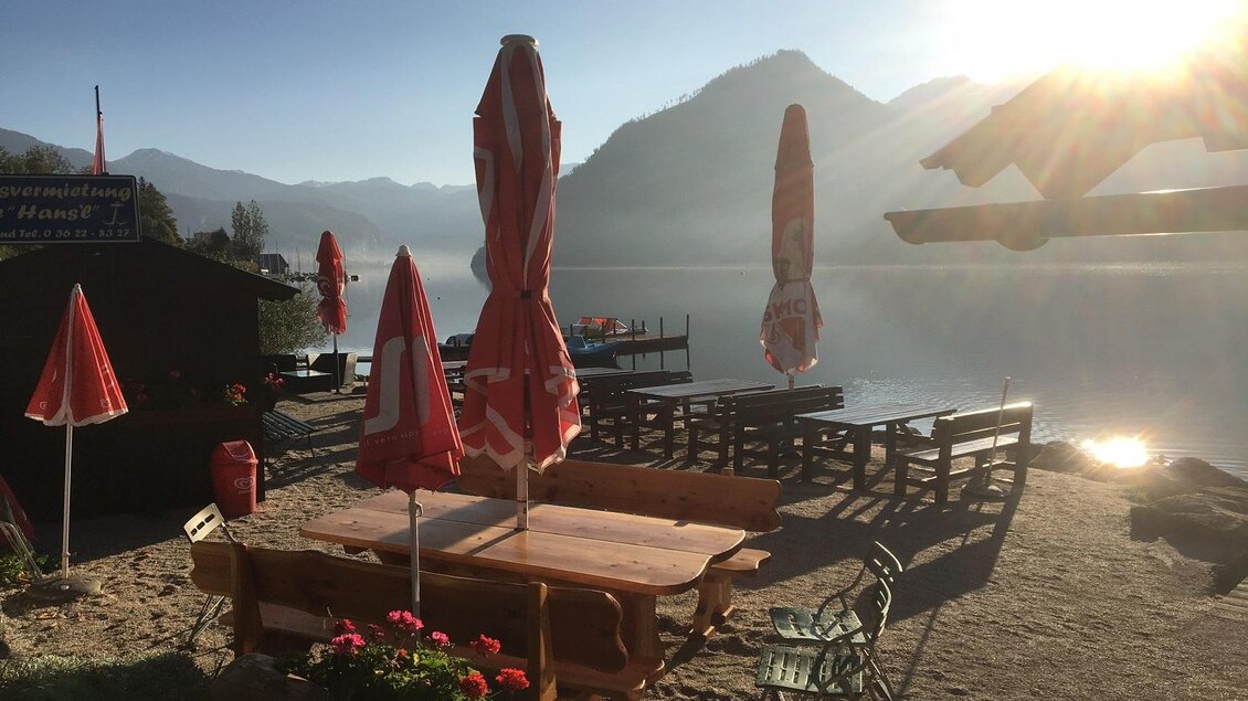 <p>Direkt am Seeufer des Grundlsees befindet sich die Terasse der Seelaube mit Blick auf das glasklare Wasser. Rote Sonnenschirme bieten Schatten in der Morgensonne.</p> | © Loitzl