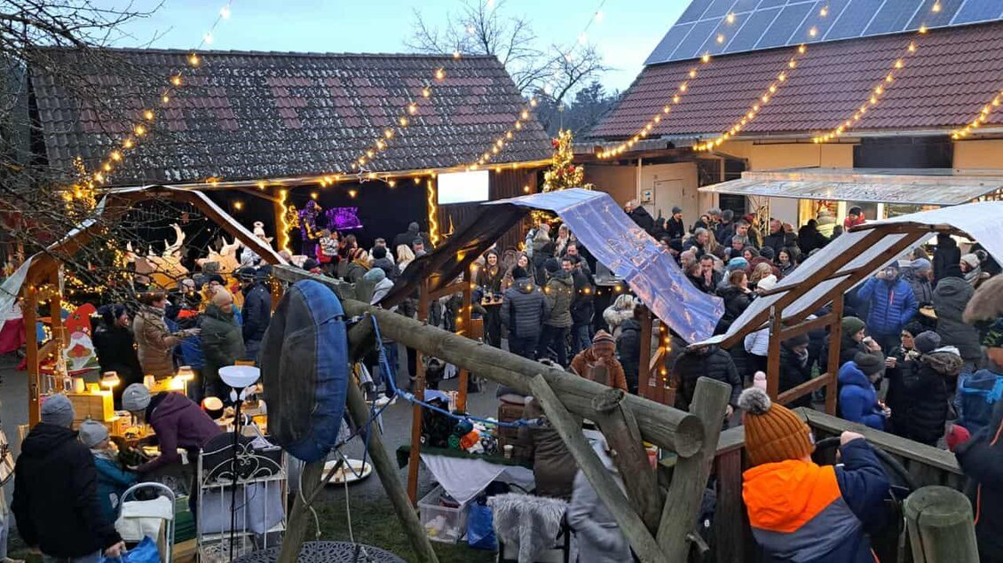 Besucher genießen den festlich beleuchteten Christkindlmarkt Da Finz in Mooskirchen mit Ständen und Lichtern. | © Da Finz