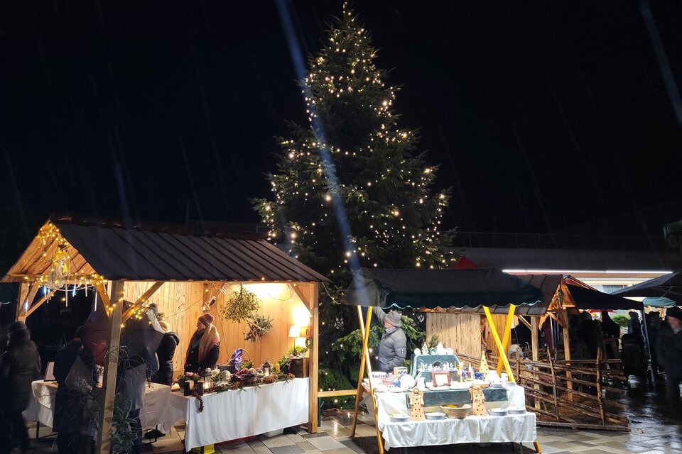 Ein festlicher Weihnachtsmarkt bei Nacht mit leuchtenden Ständen und einem großen, geschmückten Baum. Die Atmosphäre ist warm und einladend. | © Birgit Friedl