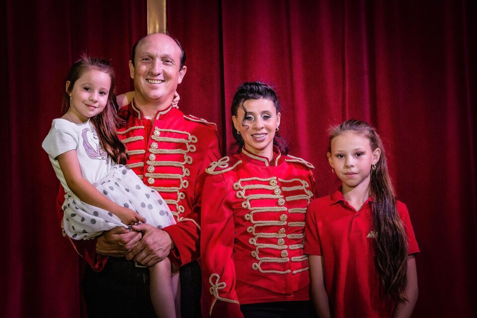 Ein Familienfoto von drei Personen in roten Kostümen vor einem roten Vorhang. Eine kleine Mädchen sitzt auf dem Arm eines Mannes, während zwei Frauen neben ihnen stehen. | © Circus Aros