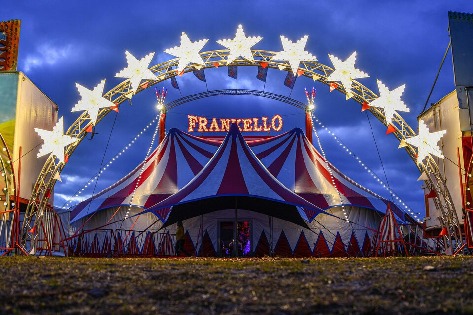 Rot-blaues Zirkuszelt des Circus Frankello mit beleuchtetem Sternenbogen und Schriftzug bei Dämmerung in Seiersberg-Pirka. | © Circus Frankello-Lukas Arnold