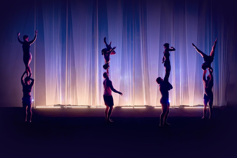 Vier Akrobatik-Duos zeigen bei Cirque Noël in Graz Hebefiguren und Handstände auf einer violett beleuchteten Bühne. | © Daniel Boud