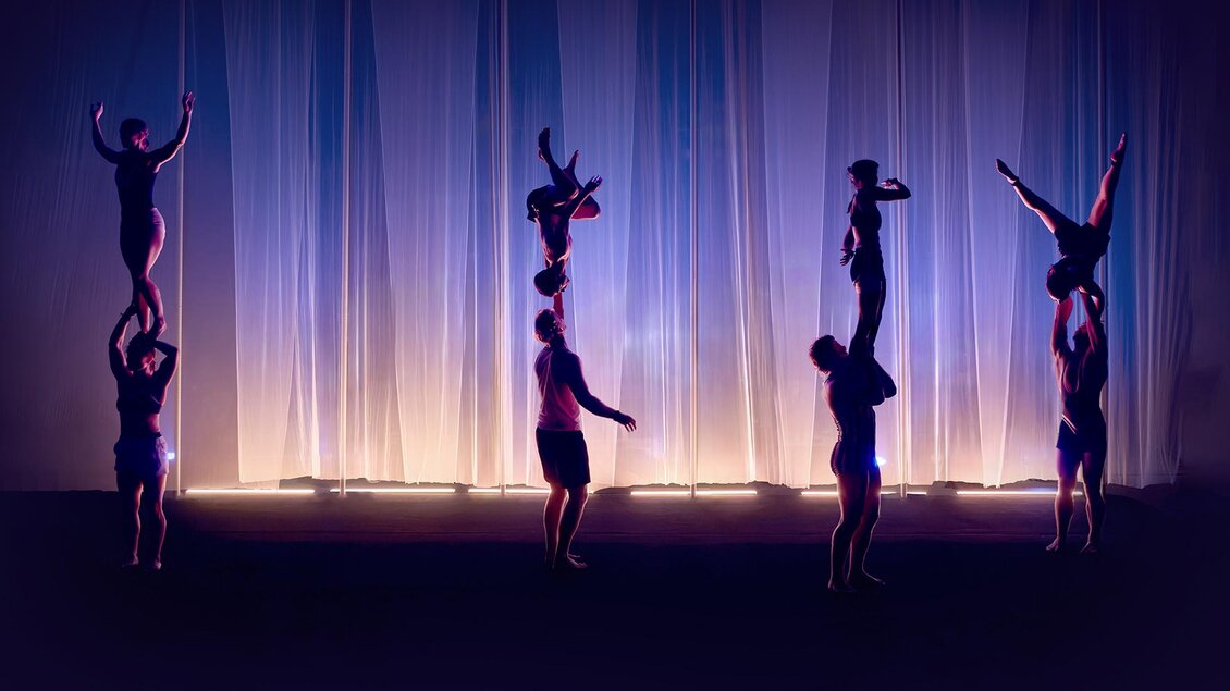 Vier Akrobatik-Duos zeigen bei Cirque Noël in Graz Hebefiguren und Handstände auf einer violett beleuchteten Bühne. | © Daniel Boud