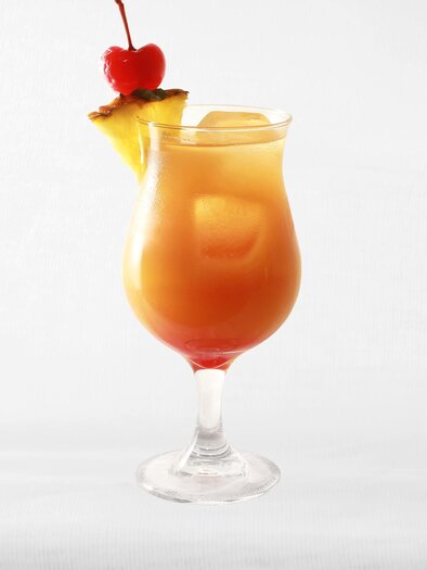 Ein bunter Cocktail in einem eleganten Glas mit einer Kirsche und Ananasscheibe als Dekoration. Der Drink hat eine leuchtende orange Farbe und sieht erfrischend aus. | © Pixabay