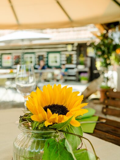 Sunny table with sunflower and wine glasses in the guest garden of Herbert's Stubn near Graz. | © Region Graz-Mias Photoart