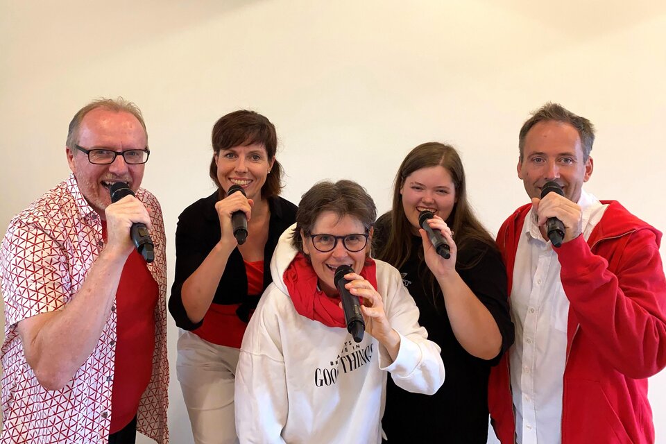 Gesangsgruppe Herzonanz mit Mikrofonen in lebendiger Performance – gemeinsame Stimme und musikalische Leidenschaft beim Curkonzert in Bad Gleichenberg. | © Herzonanz